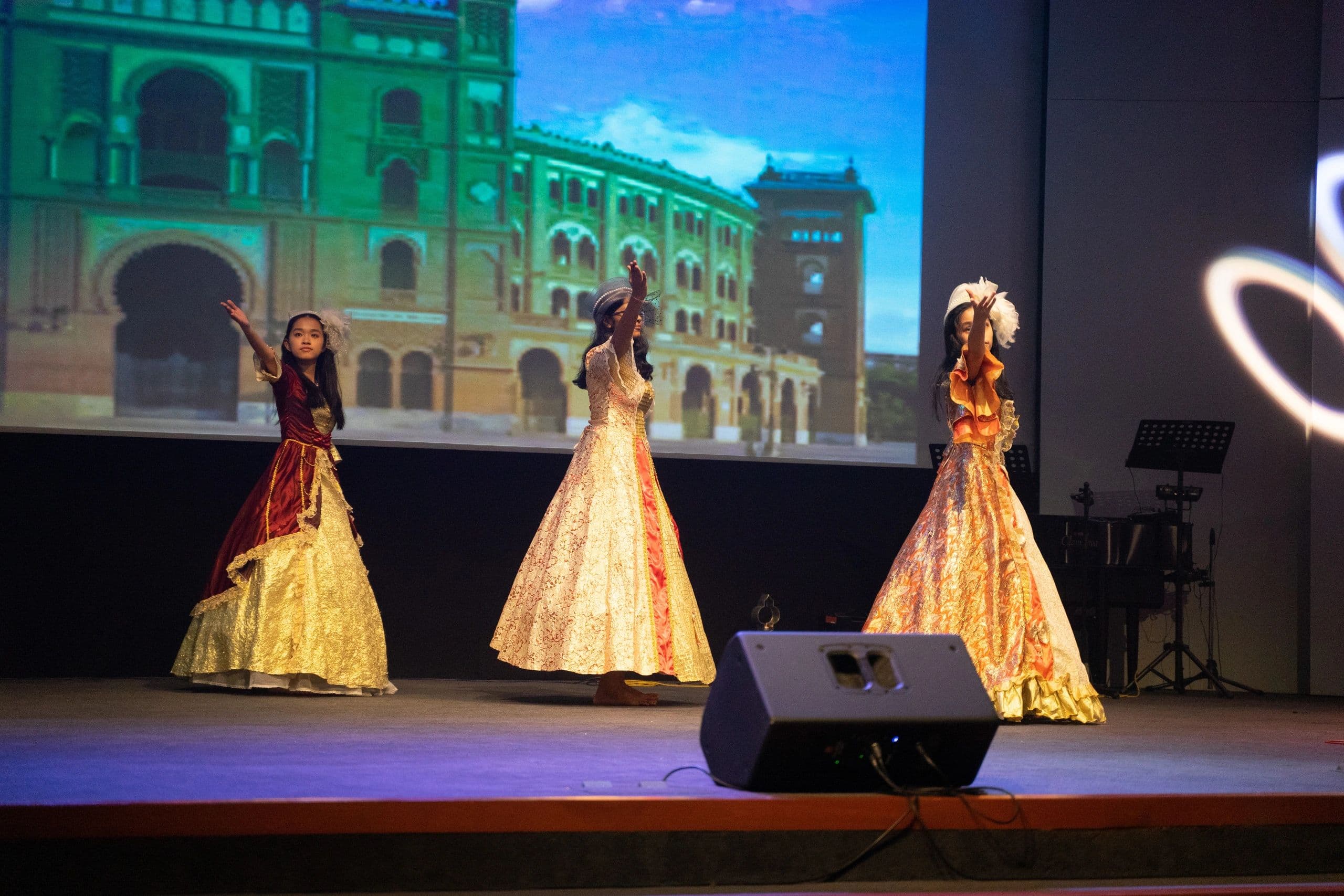 Performers in golden gowns on the school stage