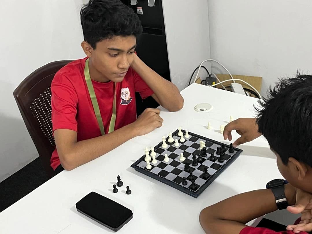 A student in a red shirt playing chess